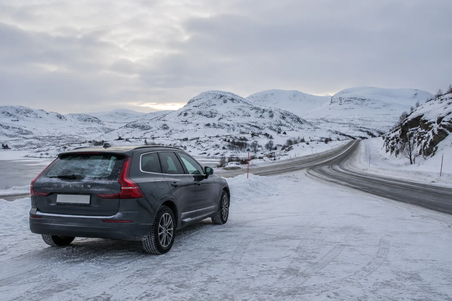 Bil på en brøytet venteplass ved en fjellvei om vinteren